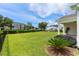 Expansive backyard with lush green grass, a black fence, and a view of surrounding buildings and blue sky at 264 Switchgrass Loop, Little River, SC 29566