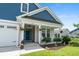 Inviting front porch with rocking chairs, hanging flower baskets, and a vibrant blue front door at 264 Switchgrass Loop, Little River, SC 29566