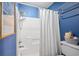 Blue bathroom featuring a shower with a white curtain and a white toilet with a basket at 315 72Nd Ave. N # A, Myrtle Beach, SC 29572