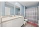 Bright bathroom featuring double sinks, white cabinets, and a shower with patterned curtain at 417 Spruce Pine Way, Conway, SC 29526