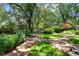Lush backyard featuring mature trees, verdant landscaping, and a brick pathway leading through the serene outdoor space at 571 Fernwood Rd., Murrells Inlet, SC 29576