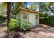 Quaint shed with painted wood siding, double doors and decorative features surrounded by vibrant greenery and brick walkway at 571 Fernwood Rd., Murrells Inlet, SC 29576