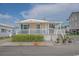 Inviting beach cottage with a covered porch, white railings, and vibrant blue shutters, offering coastal charm at 6001 - 1459 S Kings Hwy., Myrtle Beach, SC 29575