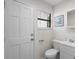 Clean bathroom with a sink, toilet, window with blinds, and a white paneled door at 6001 - Z-49 S Kings Hwy., Myrtle Beach, SC 29575