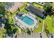 Aerial view of a sparkling community pool surrounded by lounge chairs, tennis courts, and lush landscaping at 6576 Pebble Beach Crescent, Myrtle Beach, SC 29588