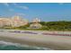 Expansive beach view of the beach with umbrellas and a distant view of the building complex at 7374 Sarteano Dr., Myrtle Beach, SC 29572