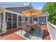 Outdoor wooden deck with seating area under umbrella, screened porch, and outdoor rug at 890 Knoll Dr., Little River, SC 29566