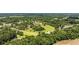 An aerial view shows a community with homes surrounded by abundant trees and vegetation, near fields and a school at 903 N Park St. Ext., Mullins, SC 29574