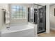 Bright bathroom featuring a soaking tub with a window and a glass-enclosed shower with black surround at 1100 Rosetta Dr., Conway, SC 29526