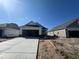 New construction home with a long driveway, showing the exterior and some surrounding construction under a clear sky at 1221 Lady Bird Way, North Myrtle Beach, SC 29582