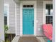 Inviting home exterior featuring a vibrant turquoise front door and a charming chair at 376 Mikita Dr., Surfside Beach, SC 29575