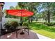 Comfortable backyard patio with an outdoor glass table and red umbrella overlooking the greenspace at 503 20Th Ave. N # 9D, North Myrtle Beach, SC 29582