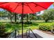 Inviting patio space with an outdoor table and chair set with a red umbrella overlooking lush green landscape at 503 20Th Ave. N # 9D, North Myrtle Beach, SC 29582