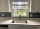 Stainless steel kitchen sink beneath a window, complemented by modern countertops and backsplash at 5310 Pauley Swamp Rd., Conway, SC 29527