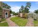 Backyard with a shed, greenhouse and brick-paved pathway surrounded by green grass and trees at 6204 Sancindy Ln., Myrtle Beach, SC 29572