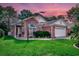 Charming brick home featuring manicured lawn and garden beds under a colorful evening sky at 1010 Swan Lake Dr., North Myrtle Beach, SC 29582