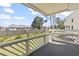 Comfortable balcony with white wood railing and scenic views of the well-manicured backyard and community at 1100 Possum Trot Rd. # F218, North Myrtle Beach, SC 29582