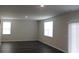 A spacious living room with two windows, sliding glass doors, and dark wood floors at 161 Londonshire Dr., Myrtle Beach, SC 29579