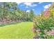 Beautiful backyard with lush green grass, flowering shrubs and mature trees on a sunny day at 3154 Shorecrest Bay Dr., Murrells Inlet, SC 29576