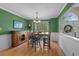 Green dining room with hardwood floors, wainscoting, a wooden table, and an open view into the foyer at 3975 River Hills Dr., Little River, SC 29566