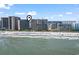 Aerial view of condo complex on beach featuring many umbrellas on the beach at 4800 S Ocean Blvd. # 520, North Myrtle Beach, SC 29582