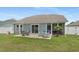A home's backyard offers a patio with seating, a screened porch, and a well-maintained lawn at 729 Bonita Loop, Myrtle Beach, SC 29588