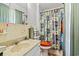 A bathroom is decorated with a patterned shower curtain, tiled walls, and vintage fixtures at 1005 S Main St., Mullins, SC 29574