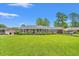 A single-story brick home features a lush green lawn, mature trees and a covered parking area at 1005 S Main St., Mullins, SC 29574