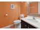 Well-lit half bath with a white sink and vanity, complemented by an orange wall at 1011 S Ocean Blvd. # 301, North Myrtle Beach, SC 29582