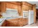 Galley kitchen features wood cabinets with white appliances including a stove, oven, and fridge at 12721 Pleasant Hill Dr., Hemingway, SC 29554