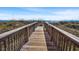 Wooden boardwalk with handrails leading to an ocean beach surrounded by grassy dunes at 1820 N Ocean Blvd. # 303D, North Myrtle Beach, SC 29582