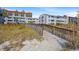Grassy path to condominium building featuring weathered boardwalk leading to a beach at 1820 N Ocean Blvd. # 303D, North Myrtle Beach, SC 29582