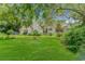 Beautiful yellow home featuring a well-manicured lawn, mature trees, and a charming front yard firepit at 189 Aspen Loop, Pawleys Island, SC 29585