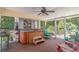 Enclosed porch featuring a hot tub, ceiling fan, and seating area with wooded backdrop at 189 Aspen Loop, Pawleys Island, SC 29585