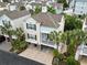 Aerial view of the beautiful beach home featuring a covered patio, balcony, golf cart storage, and a lush green landscape at 208 Millwood Dr., Surfside Beach, SC 29575