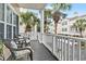 Charming balcony with outdoor seating, white railings, and views of palm trees and neighboring houses at 208 Millwood Dr., Surfside Beach, SC 29575