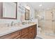 A well-appointed bathroom with double sinks, granite countertops, and glass enclosed shower provides spa-like experience at 208 Millwood Dr., Surfside Beach, SC 29575