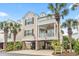 Charming two-story home with a front porch and covered parking under the house with palm trees at 208 Millwood Dr., Surfside Beach, SC 29575