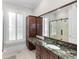 Bright bathroom featuring granite countertop, wood cabinets, a large mirror and natural light from shuttered windows at 288 Tipperary Pl., Pawleys Island, SC 29585