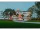 Beautiful white home with symmetrical facade, blue shutters, palm trees, and well manicured lawn at dusk at 288 Tipperary Pl., Pawleys Island, SC 29585