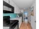 Well-equipped kitchen with white cabinets, a turquoise backsplash, and modern black appliances at 3000 N Ocean Blvd. # 1127, Myrtle Beach, SC 29577