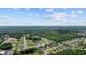Breathtaking aerial view of homes bordering a lake, encircled by lush trees, under a partly cloudy sky at 305 Forestbrook Cove Circle, Myrtle Beach, SC 29588