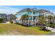 The beautiful teal home features multiple stories and a well-manicured front yard with palm trees at 350 Saint Julian Ln., Myrtle Beach, SC 29579