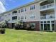 Rear exterior of the condominium featuring a lawn, brick foundation, and screened in porch at 3965 Forsythia Ct. # 202, Myrtle Beach, SC 29588