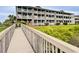 Exterior view from a walkway to multi-story condos with decks, enhanced by landscaping at 4522 N Plantation Harbour Dr. # E7, Little River, SC 29566