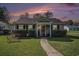 Charming single story home with manicured lawn and covered entrance featuring a colorful sunset backdrop at 6570 Pebble Beach Crescent, Myrtle Beach, SC 29588