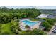 Aerial view of a community pool featuring lounge chairs, umbrellas, and lush landscaping near lake and buildings at 155 Chenoa Dr. # E, Murrells Inlet, SC 29576