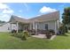 A spacious back patio with a dining set, barbecue grill, and manicured garden beds at 232 White Water Loop, Conway, SC 29526