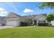 Home exterior featuring a two-car garage, well-maintained lawn, and charming front entrance with mature landscaping at 232 White Water Loop, Conway, SC 29526