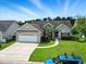 An exterior, elevated view of a home with a two car garage, manicured lawn, and a blue car in the driveway at 232 White Water Loop, Conway, SC 29526